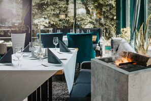 A dining area with a table set for two, chairs, and a built-in fireplace. - Parkhotel Waldschlösschen (Annaberg-Buchholz)