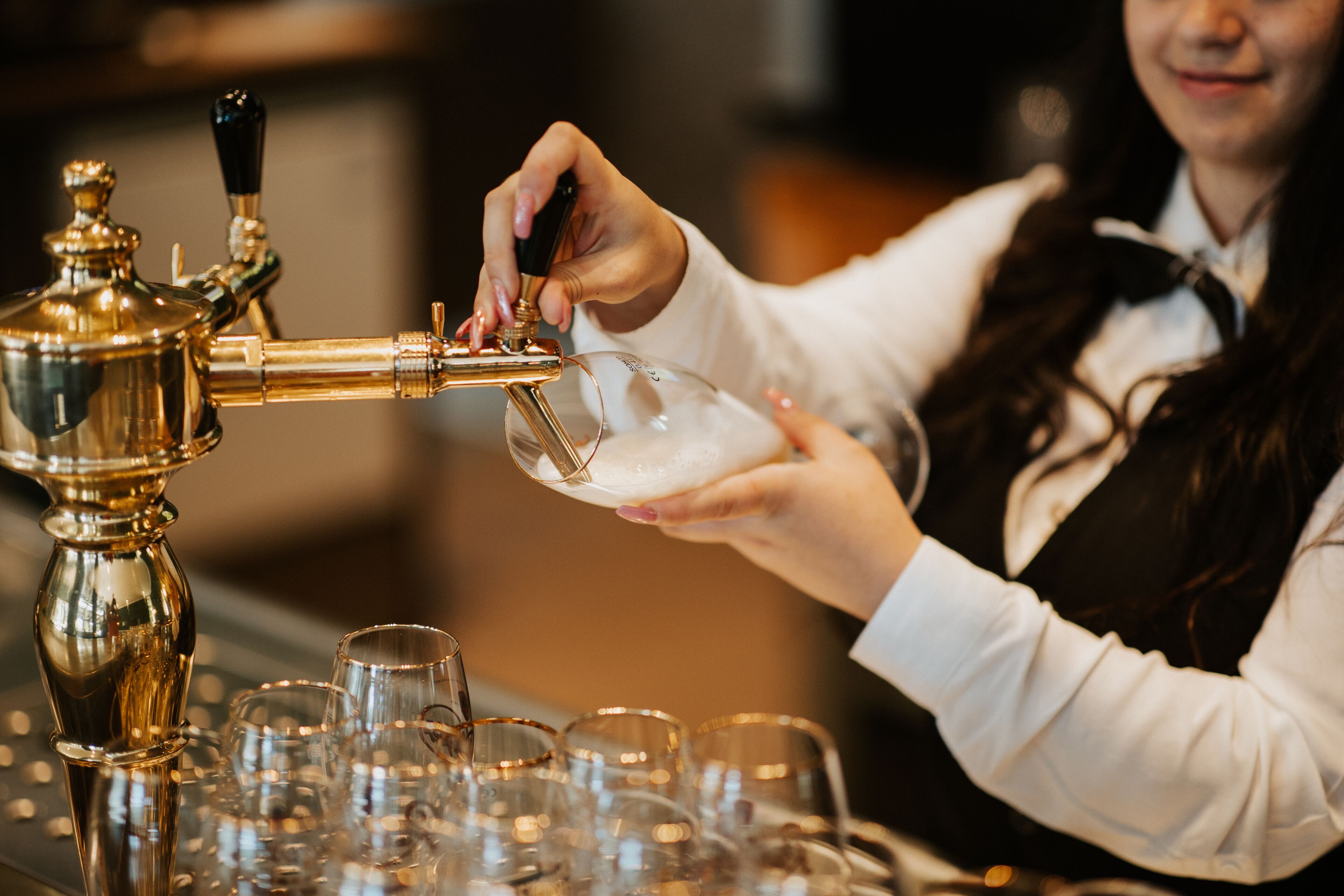 A person pouring a drink from a tap into a glass.
