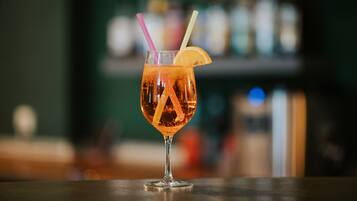 Um cocktail com uma fatia de limão e canudos num copo sobre o balcão do bar.