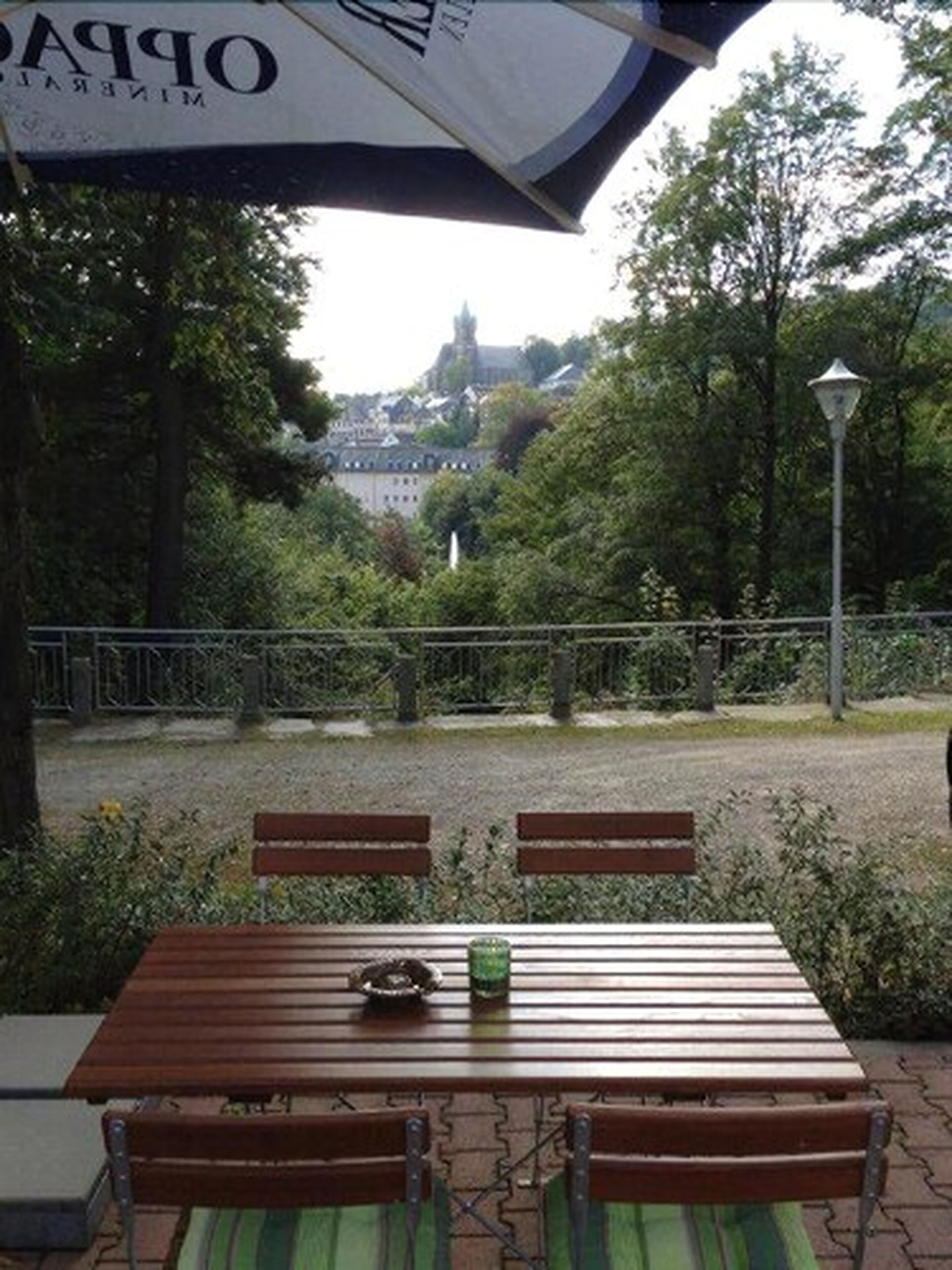 An outdoor seating area with a table and chairs, a lamp post, and a view of a building in the background.