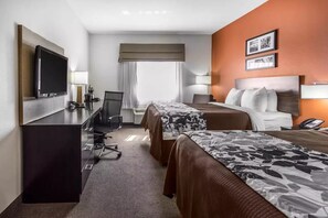 A hotel room with two beds, a desk with a computer, a TV, and a phone.