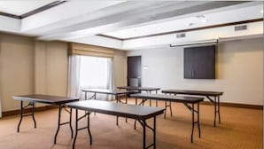 A conference room with six tables and chairs, a projector screen, and a window with curtains. - Sleep Inn & Suites Lubbock West (Lubbock)