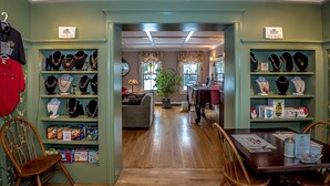 Una tienda de regalos con estanterías llenas de joyería y una zona de comedor con sillas y una mesa de madera.
