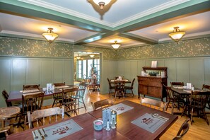 A dining area with wooden tables and chairs, a wooden buffet, and decorative wall sconces. - Cranmore Inn (North Conway)