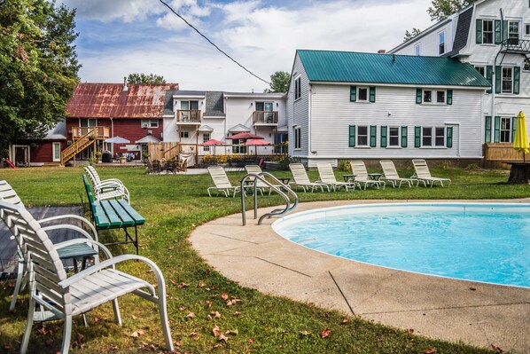 Un espace piscine avec des chaises longues et un barbecue.