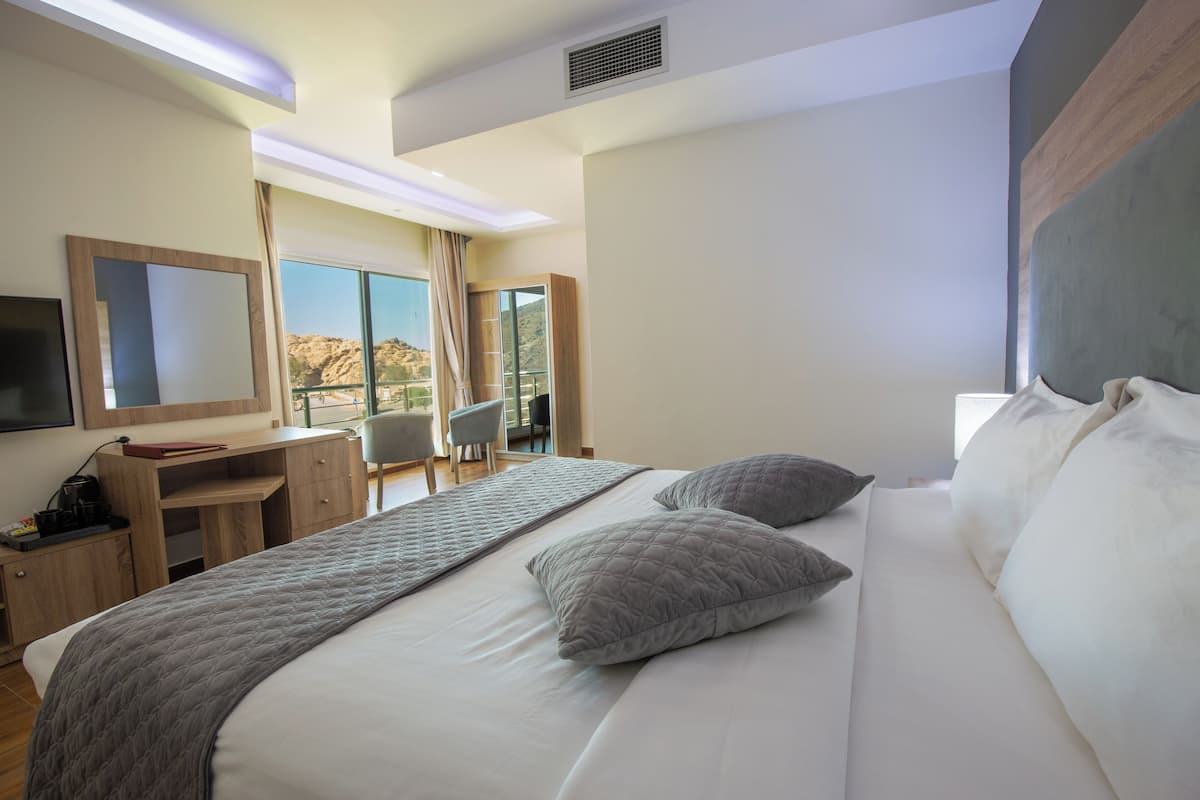 A hotel room with a large bed, a desk, a chair, and a TV.