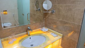 Un baño con lavamanos de mármol, espejo y zona de ducha.