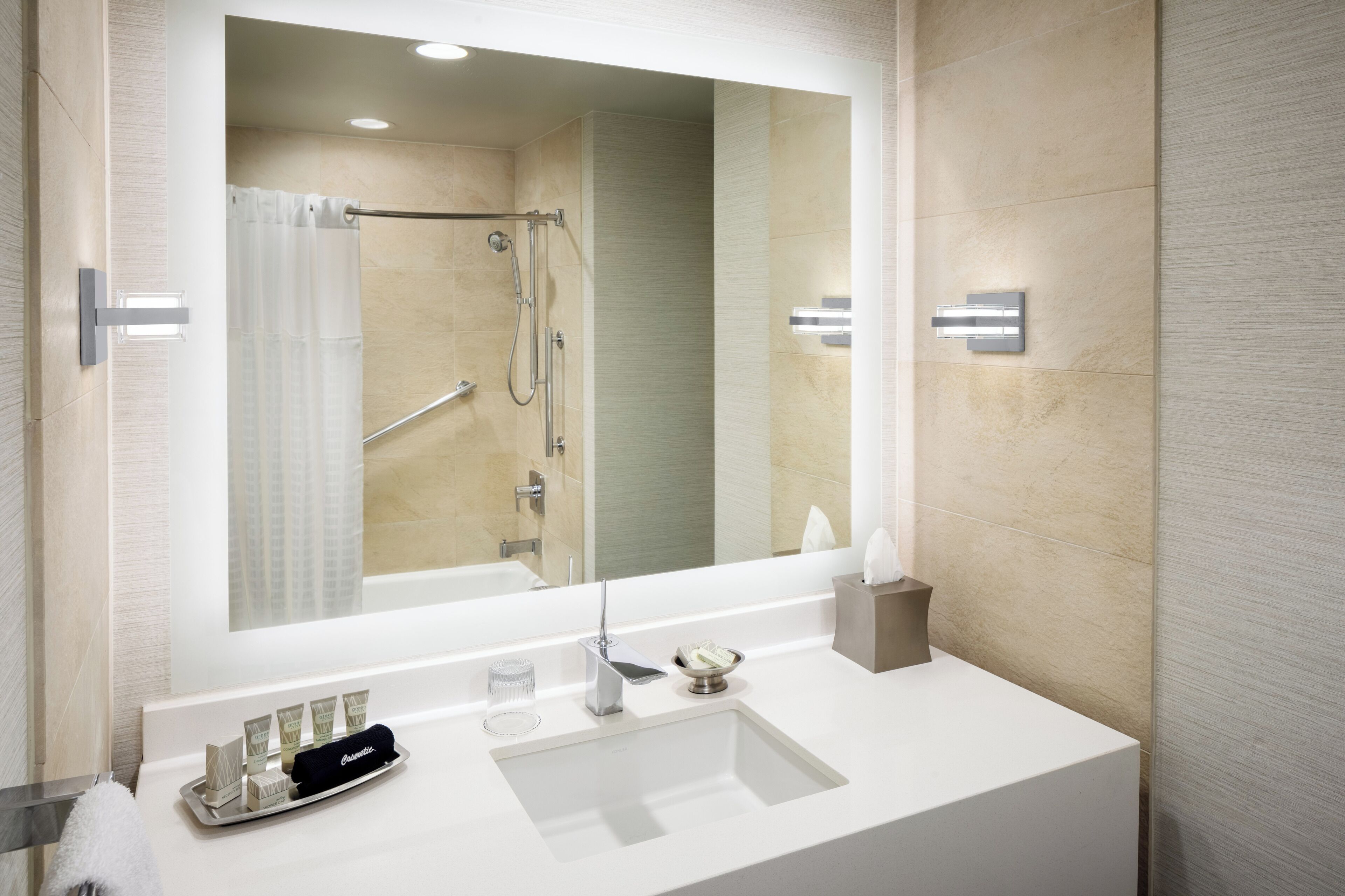A modern bathroom with a large mirror, a white sink, and a shower area.