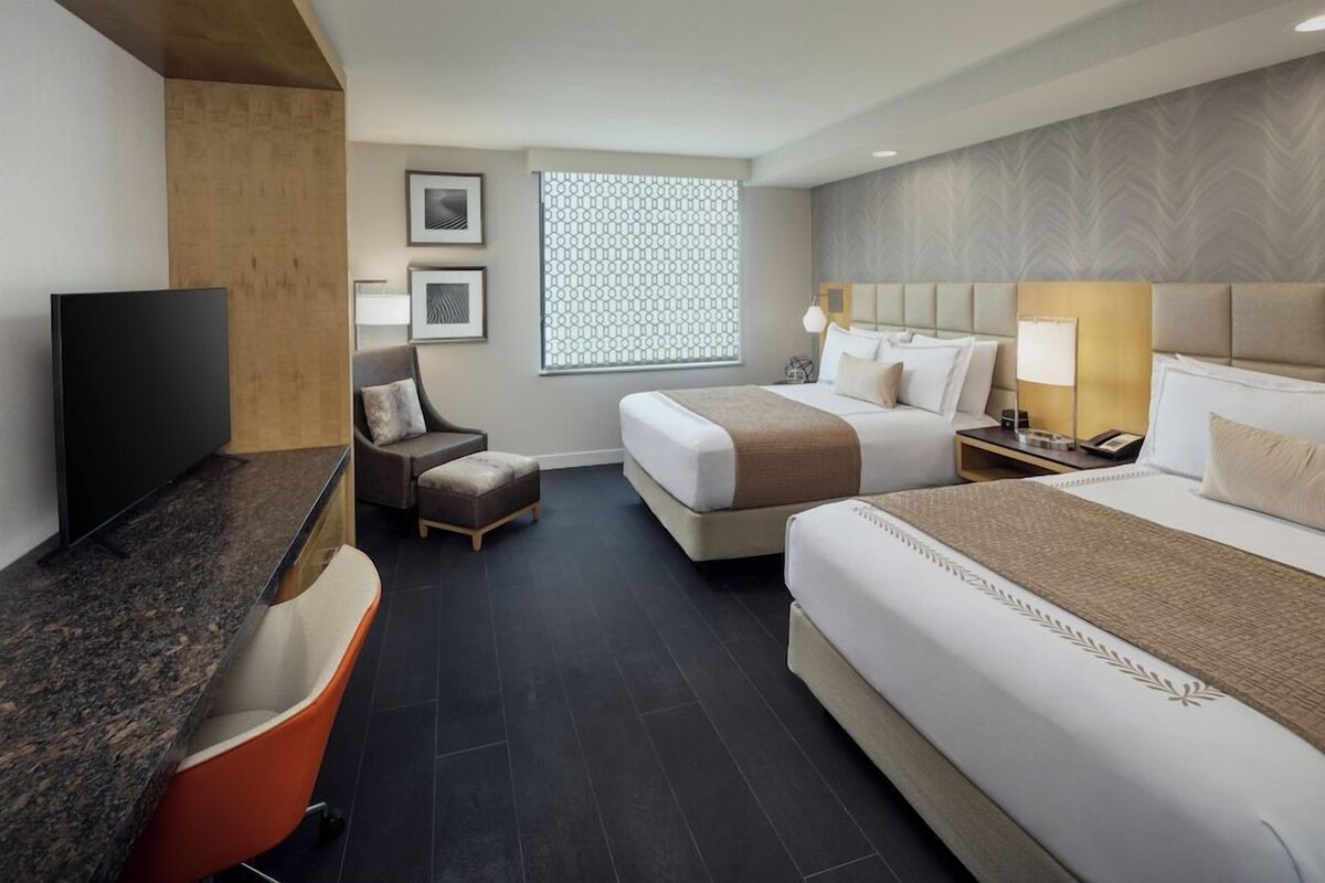 Habitación de hotel con dos camas, televisor, escritorio y silla.