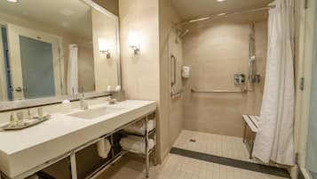 A modern bathroom with dual sinks, a walk-in shower, and a large mirror.