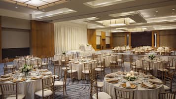 A large banquet hall with multiple round tables set for dining, arranged in a spacious layout with high ceilings and modern lighting.