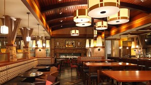 A restaurant interior with wooden beams, round tables, and hanging pendant lights. - The Hotel at Arundel Preserve (Hanover)