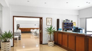 Un hall d’hôtel comprenant un comptoir d’accueil, un espace salon et une grande fenêtre.