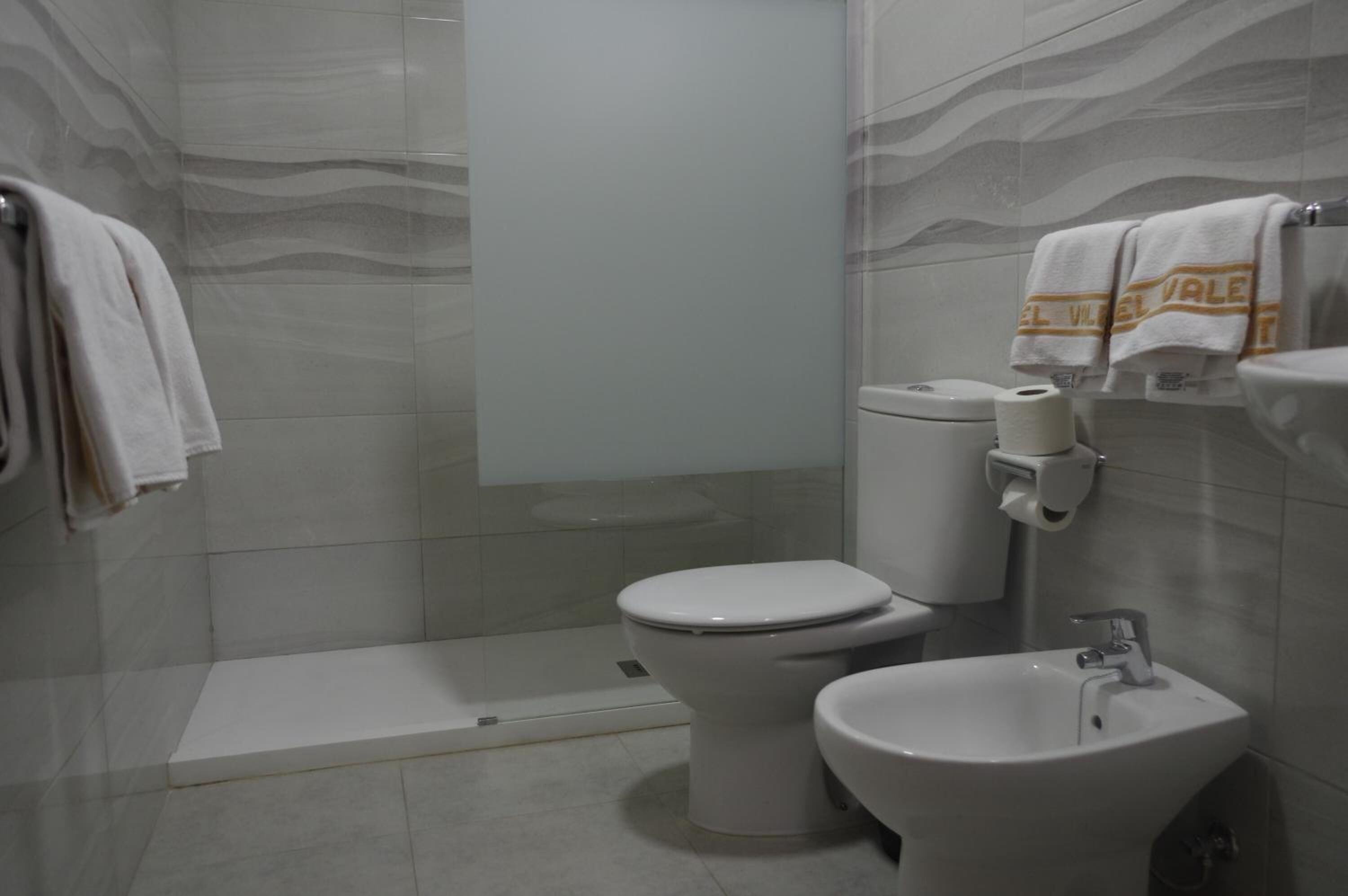 A modern bathroom with a toilet, bidet, and sink.