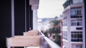 Un balcon avec une balustrade en bois donnant sur un paysage urbain.