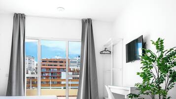 Hotellihuone, jossa on suuri ikkuna, työpöytä, tuoli ja televisio.