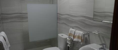 Un baño moderno con ducha de vidrio, inodoro y lavamanos.