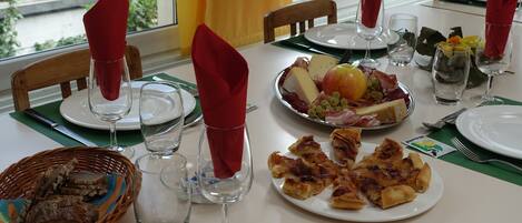 A dining table set with plates, glasses, and a basket of bread.