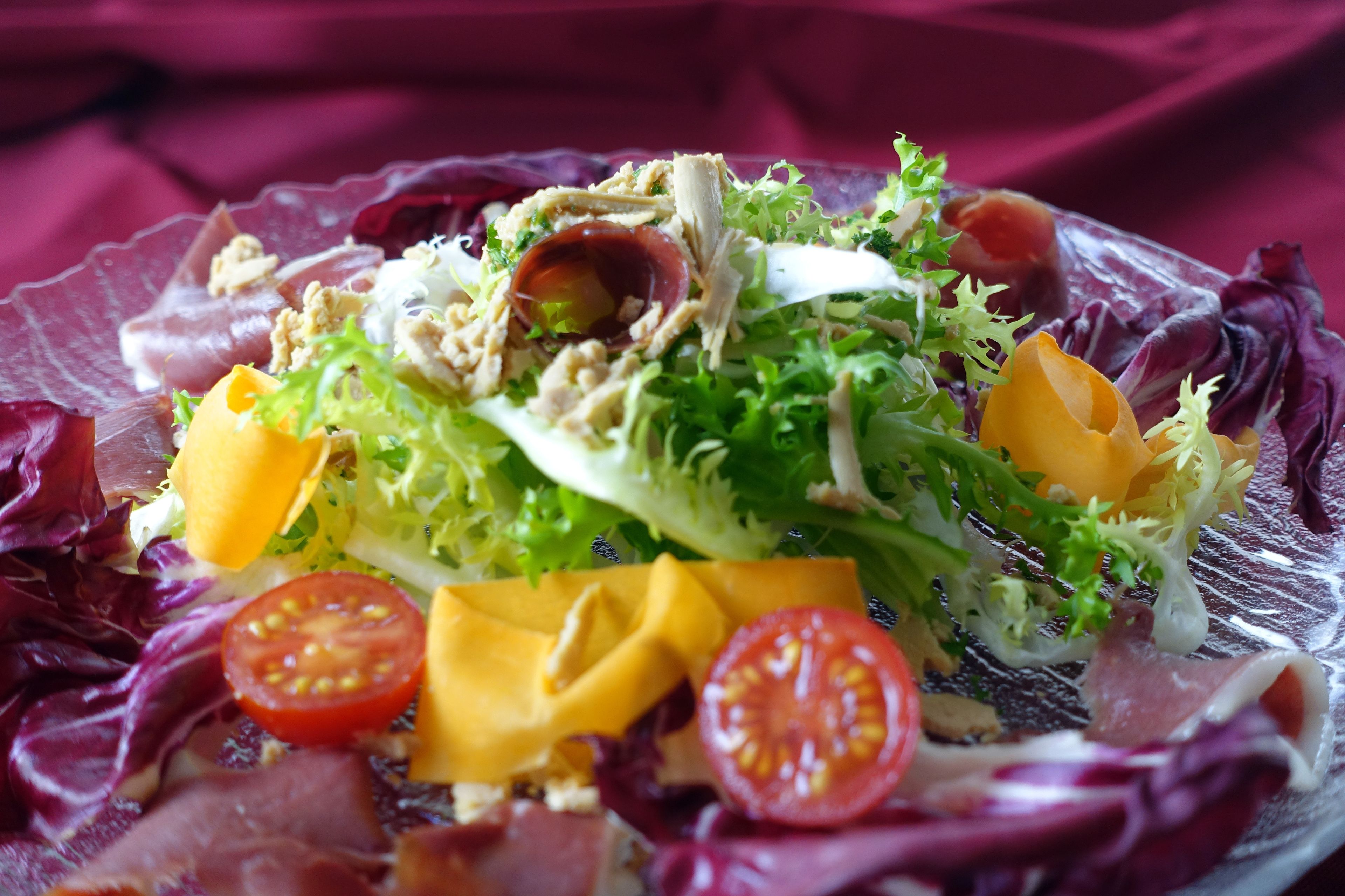 A salad with various ingredients on a clear glass plate.