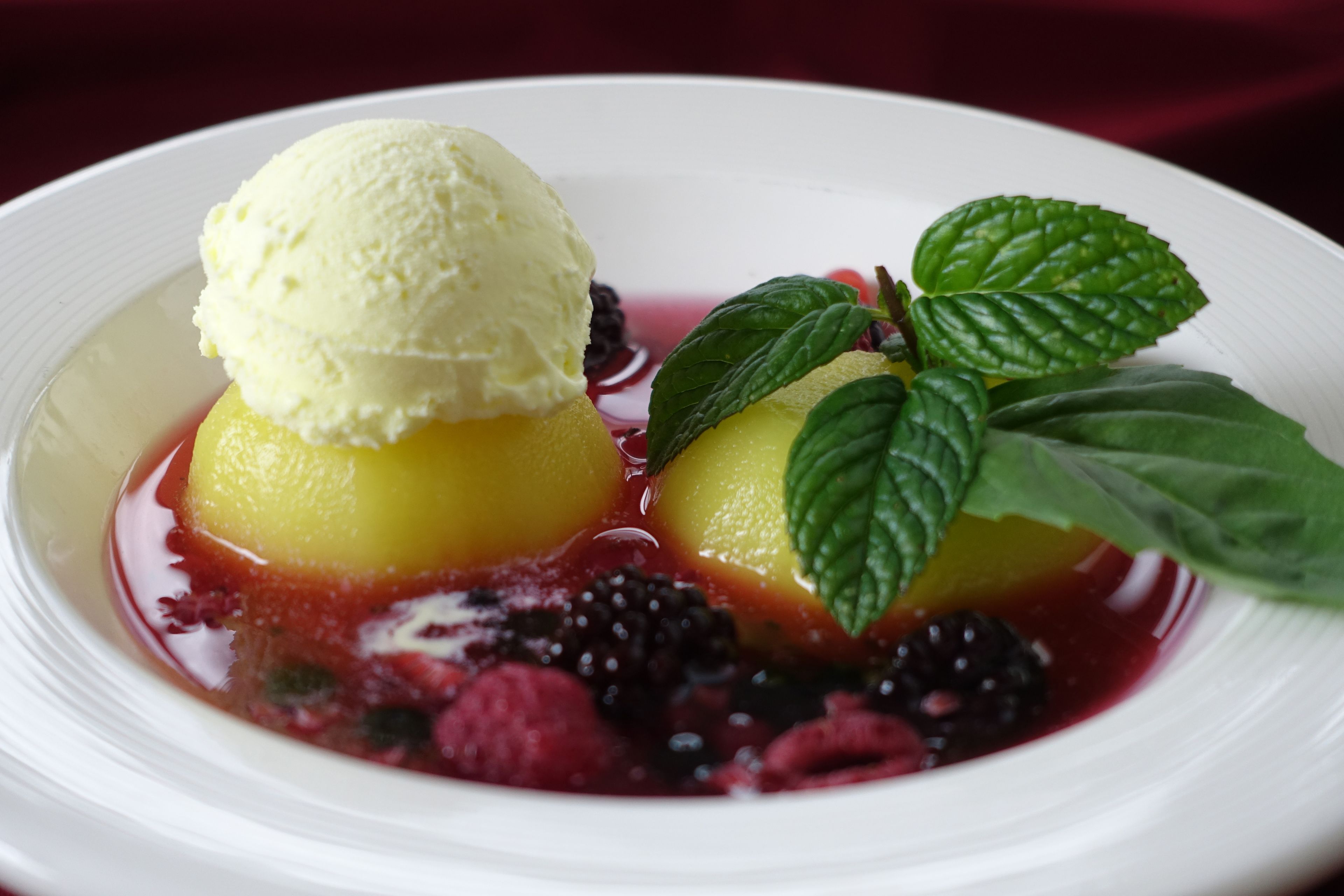 A dessert with ice cream and berries on a white plate.