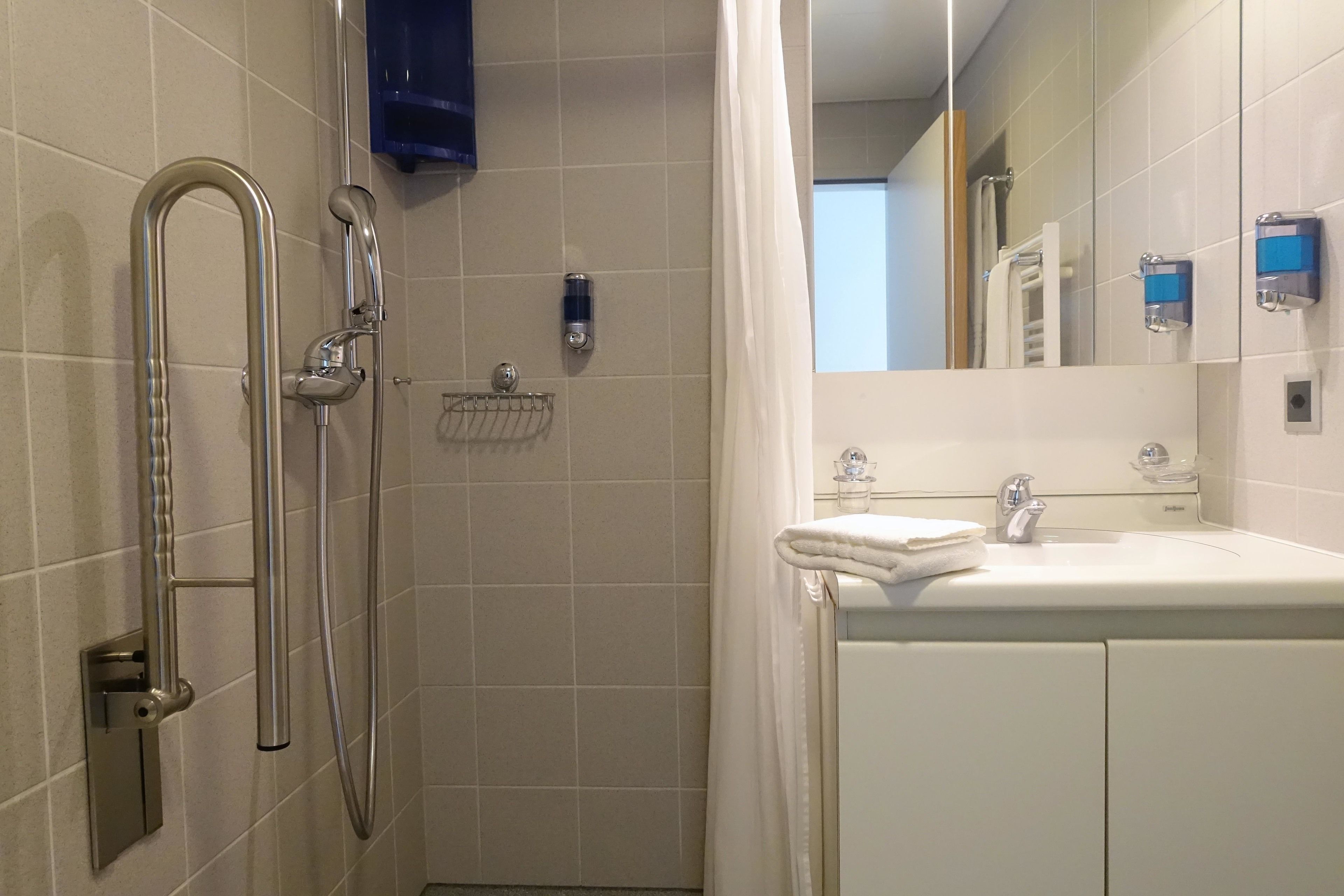 A bathroom with a shower, a sink, and a mirror.