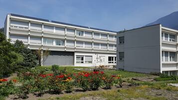 A modern building with multiple floors, large windows, and solar panels on the roof.