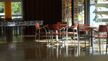 A cafe with a long counter, red chairs, and a wall of postcards.