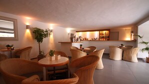 A modern interior with wicker furniture, a bar area, and potted plants.