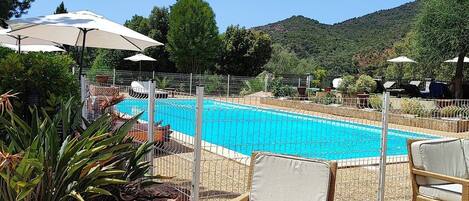 Een buitenzwembad, parasols voor strand/zwembad