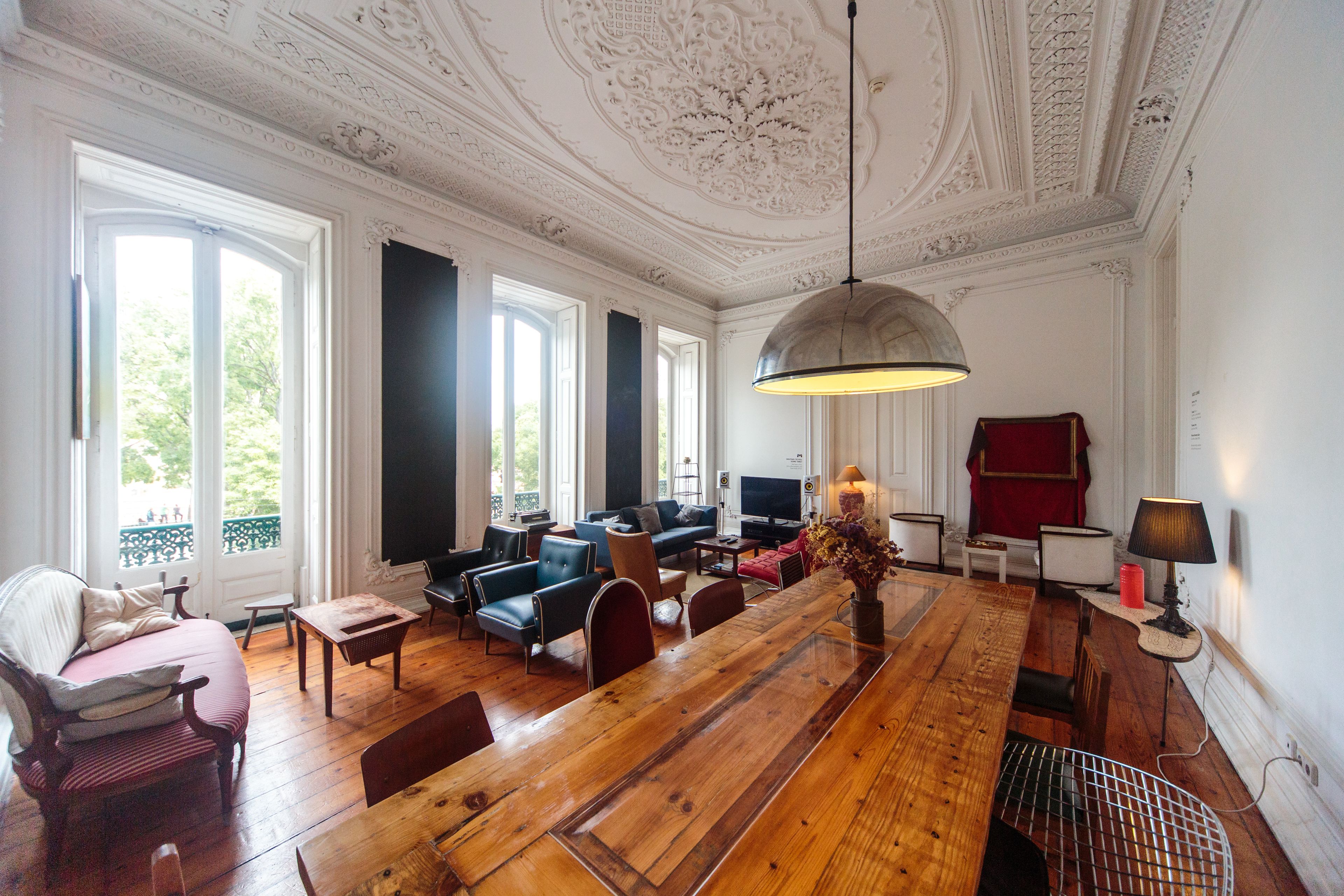 A spacious room with a wooden dining table, comfortable seating, a television, and a decorative ceiling.