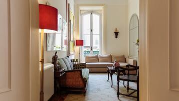 A room with a sofa, a chair, a lamp, a mirror, and a window.