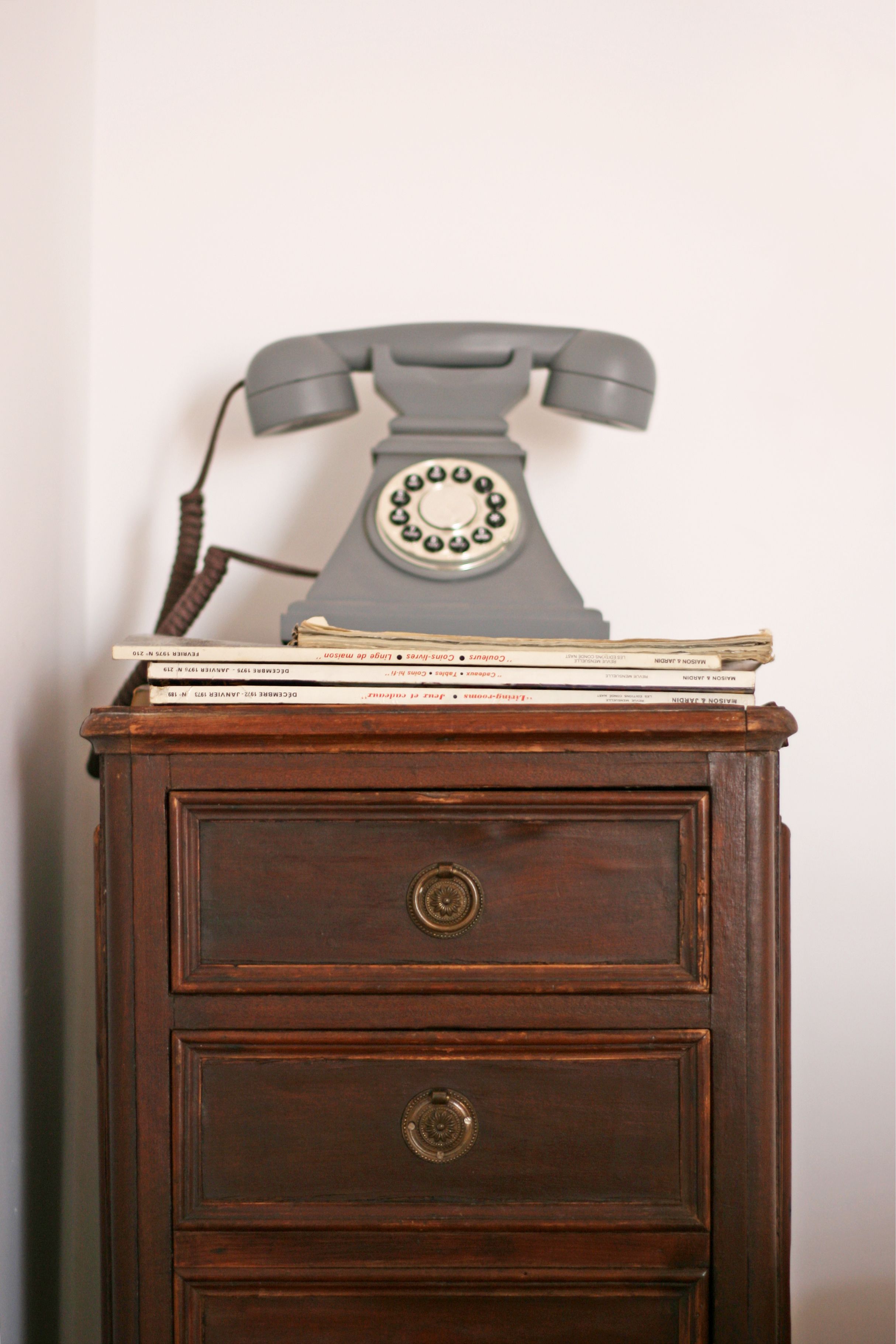 A wooden dresser with a rotary dial telephone on top.