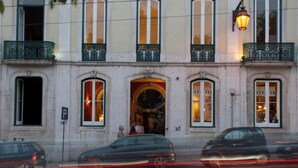 A building with multiple windows and balconies, a street in front, and cars passing by. - Independente Príncipe Real (Lisbon)