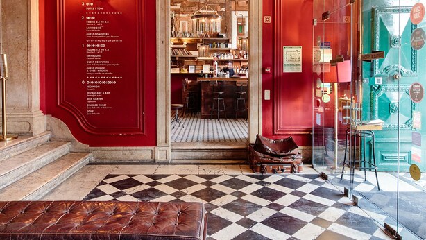 A hotel lobby with a red wall, a checkered floor, and a reception desk. - Independente Príncipe Real (Lisbon)