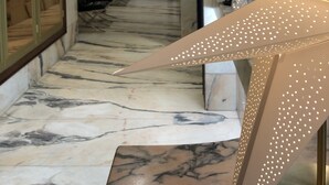 Un pasillo de hotel con suelo de mármol, un gran aplique decorativo y vistas al vestíbulo.