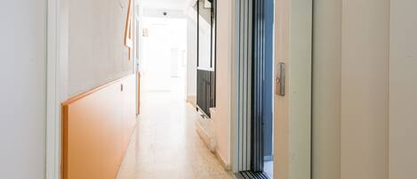 A hallway with a tiled floor, a wooden panel on the left, and a sliding door on the right.