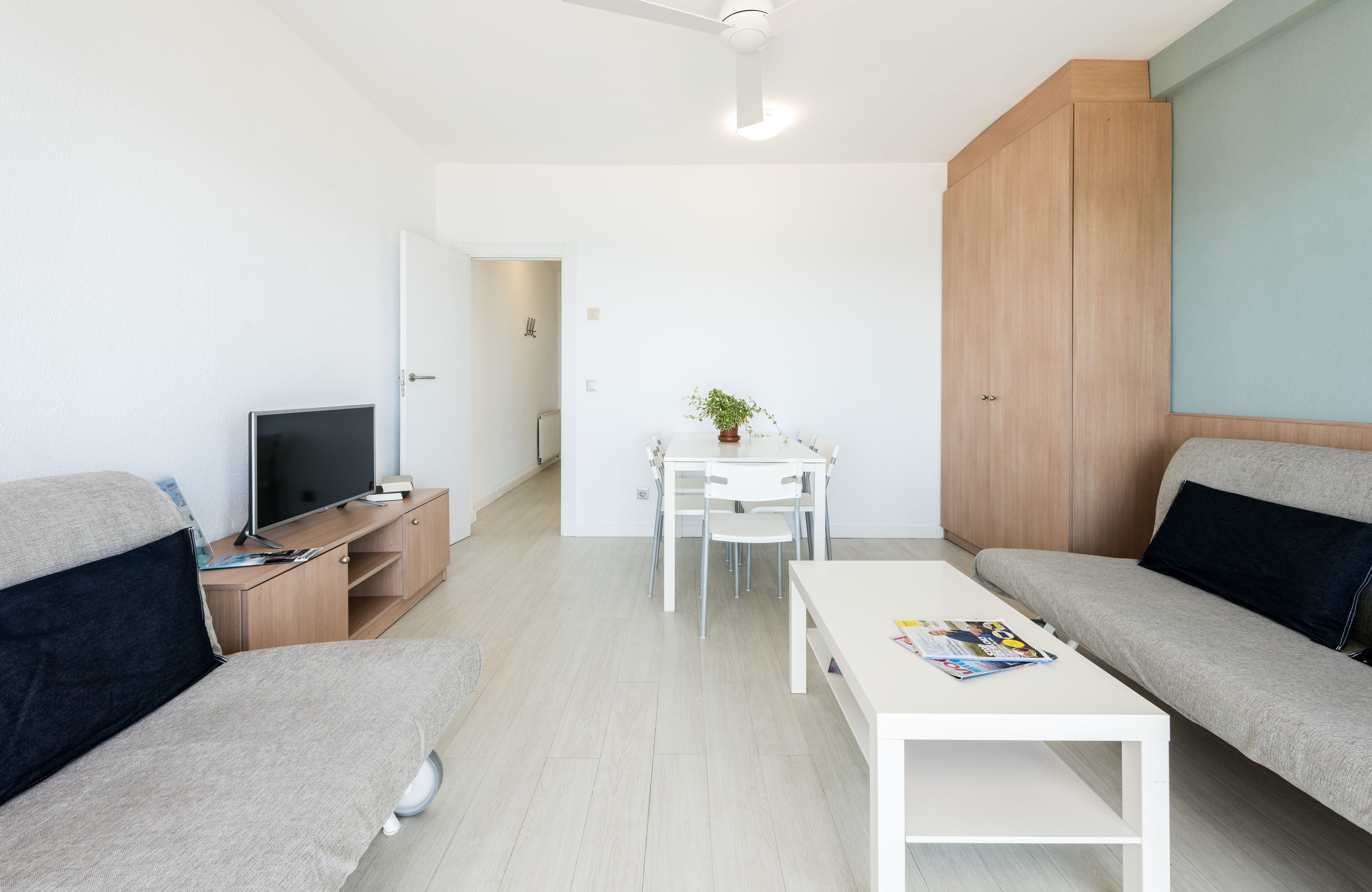 A modern living room with a flat-screen TV, a coffee table, and two sofas.