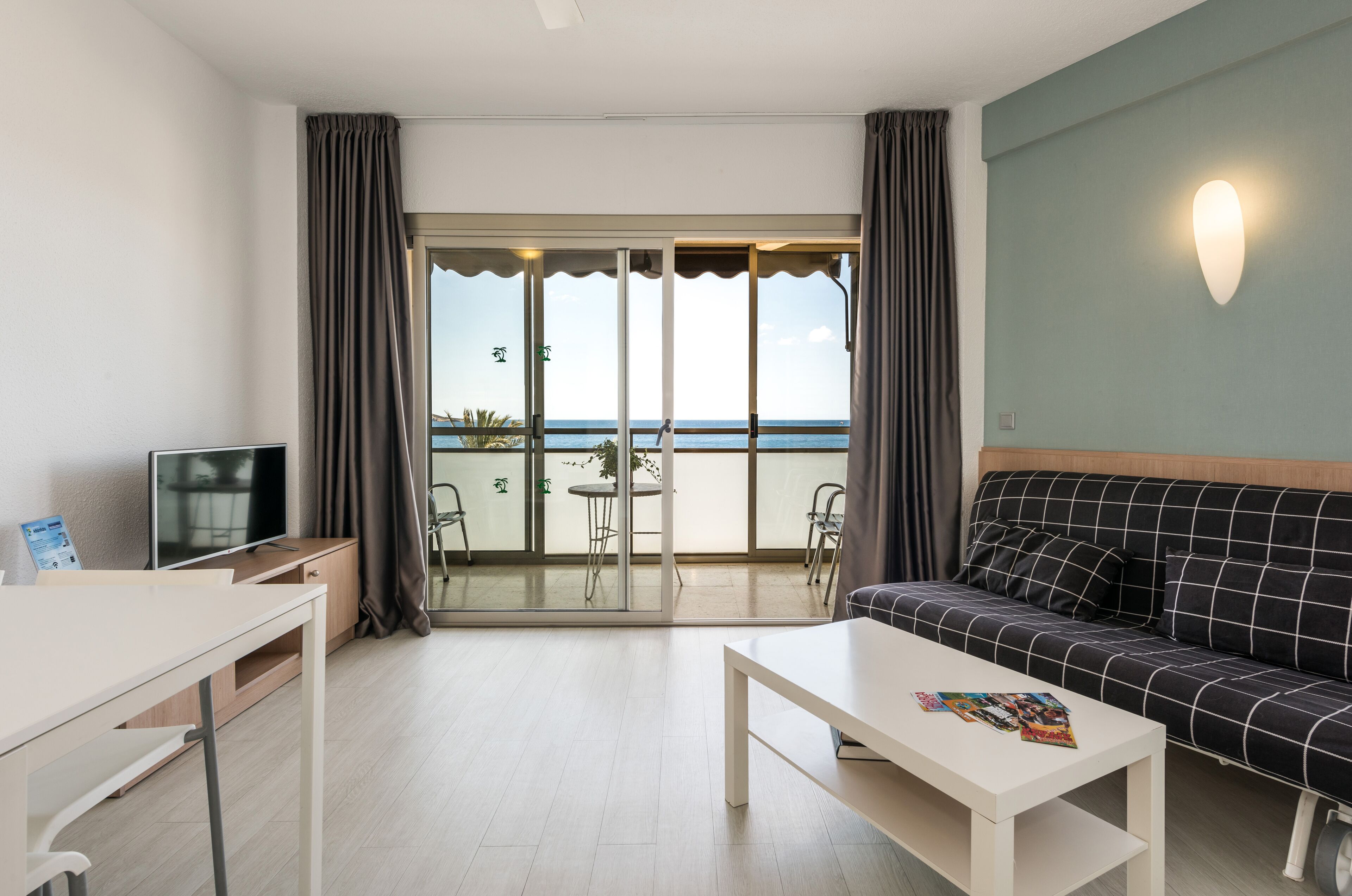 A modern room with a balcony, a sofa, a TV, and a dining table.