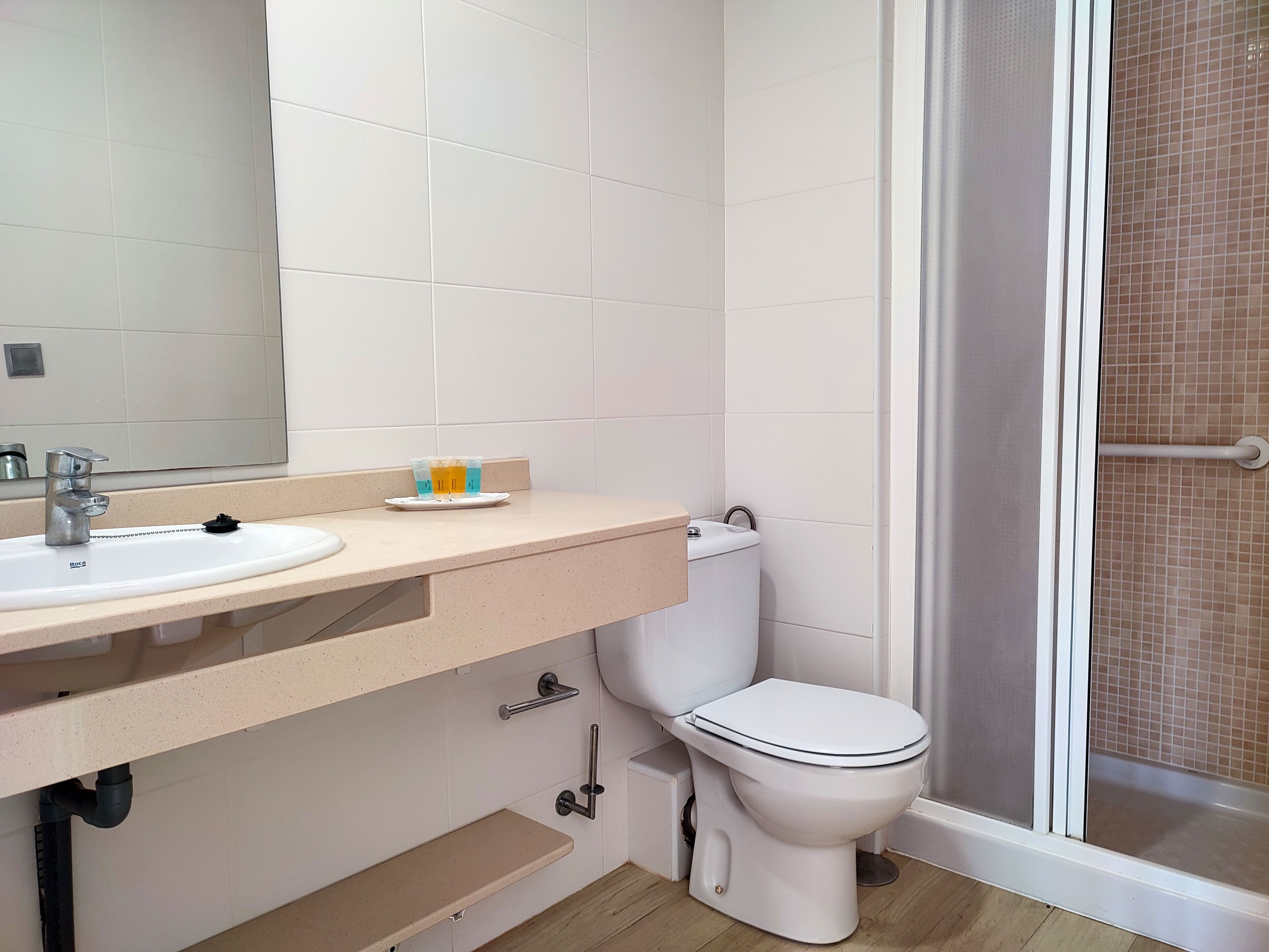 Une salle de bain équipée d’un lavabo, d’un miroir, de toilettes et d’un espace douche.