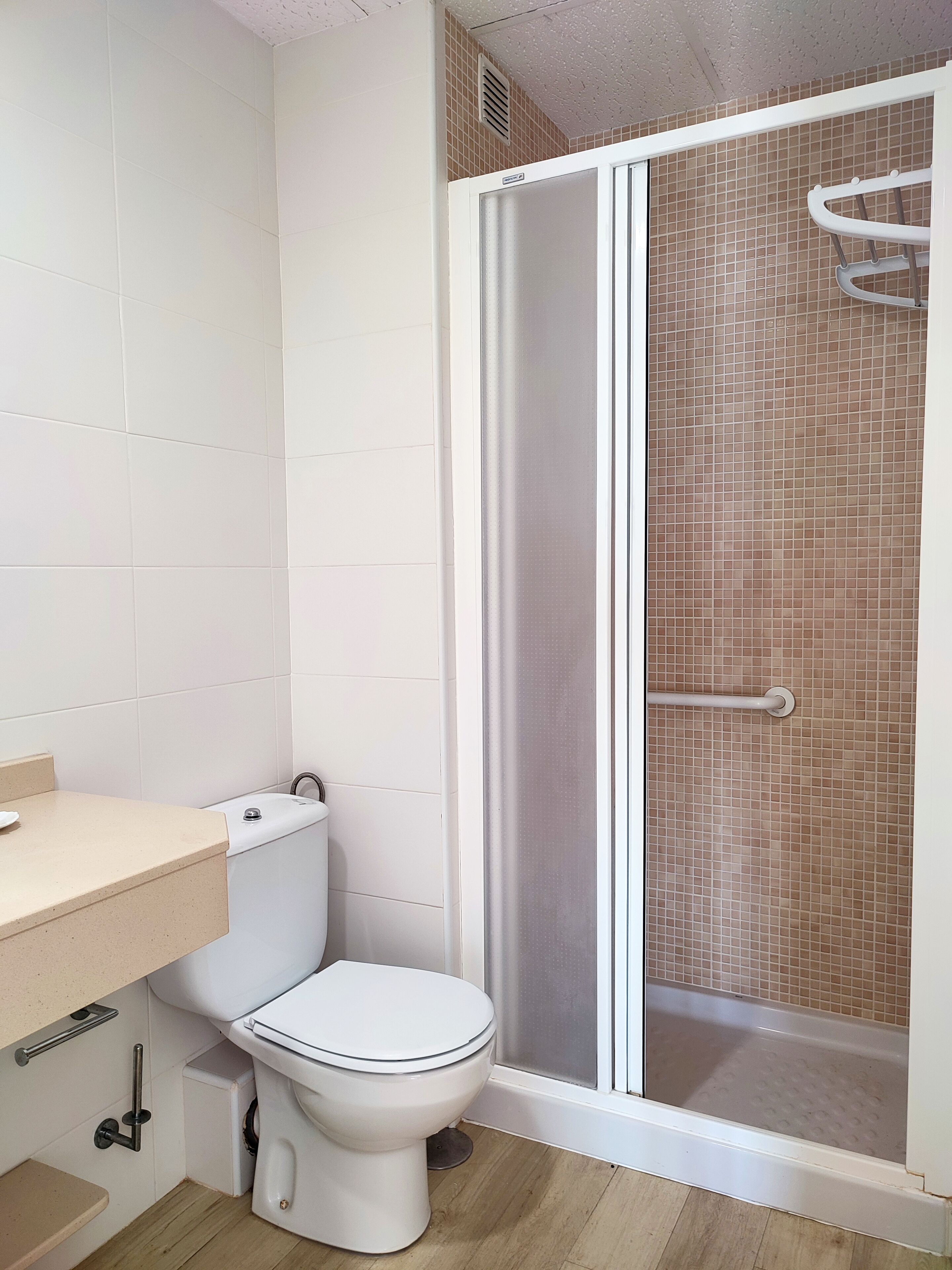 A bathroom with a toilet, a shower enclosure, and a sink.
