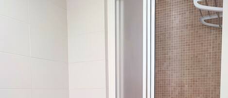 A bathroom with a toilet, a shower enclosure, and a sink.