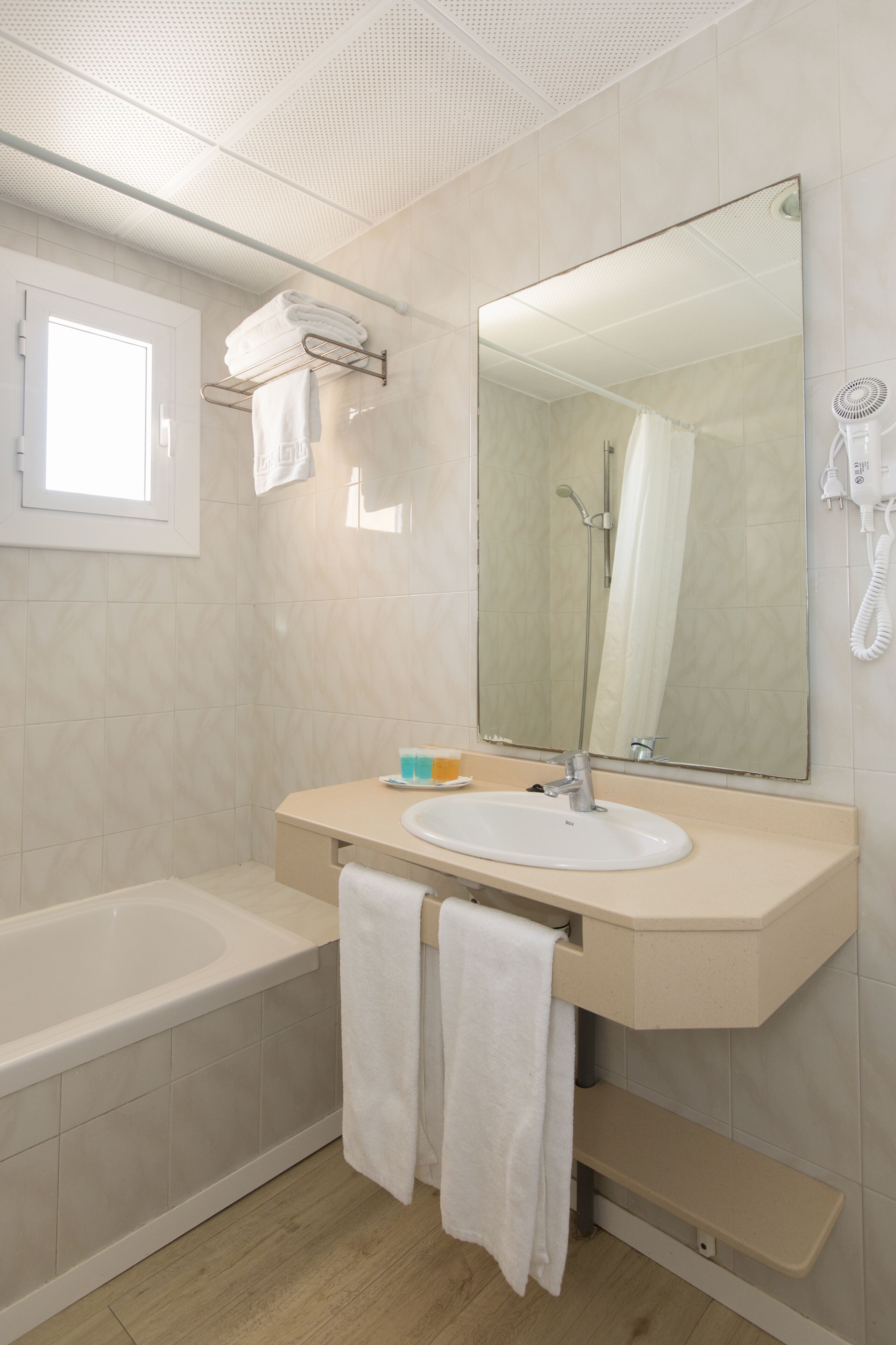 A modern bathroom with a bathtub, a sink, a large mirror, and a towel rack.