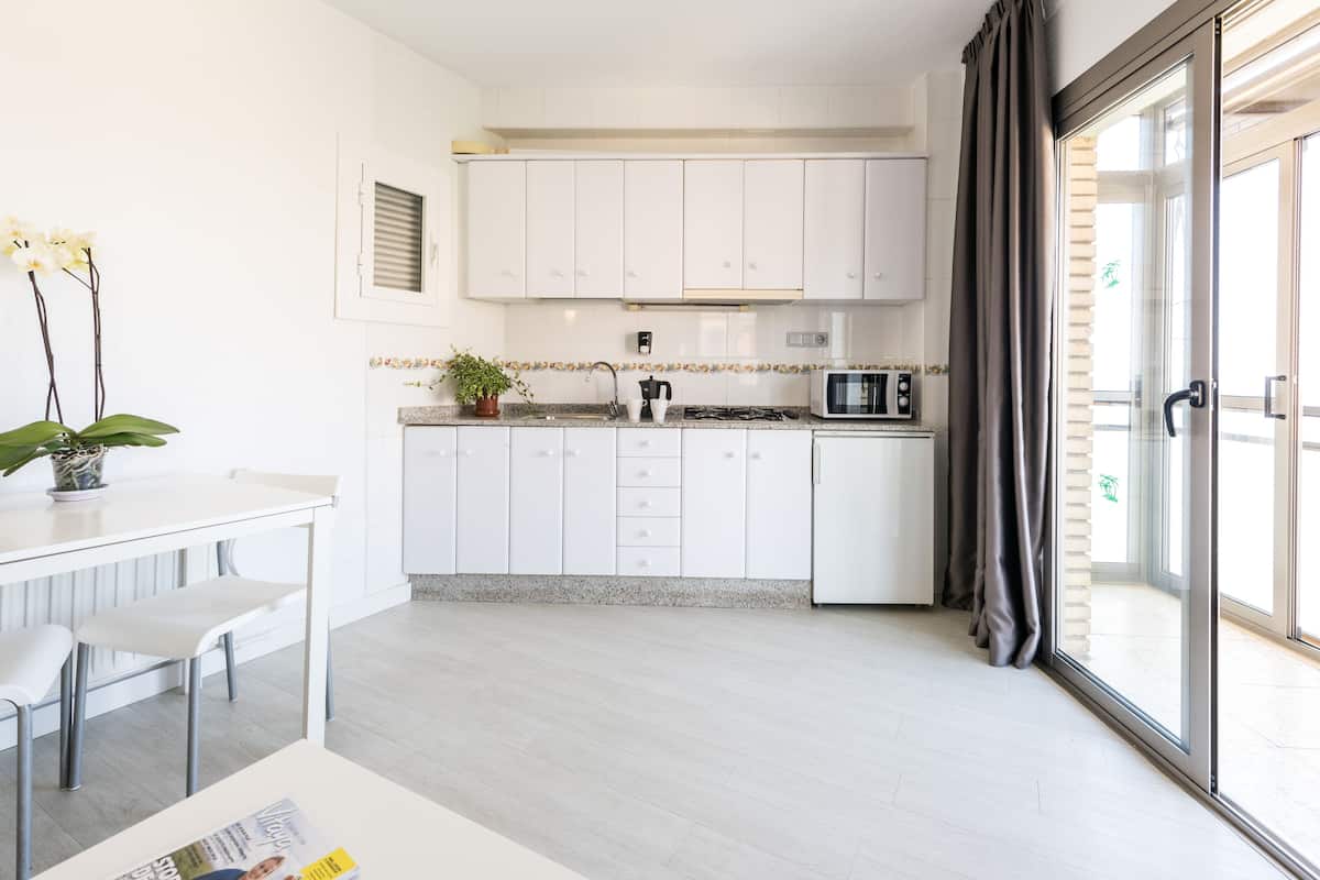 A modern kitchen with white cabinets, a microwave, and a dining area with a table and chairs.