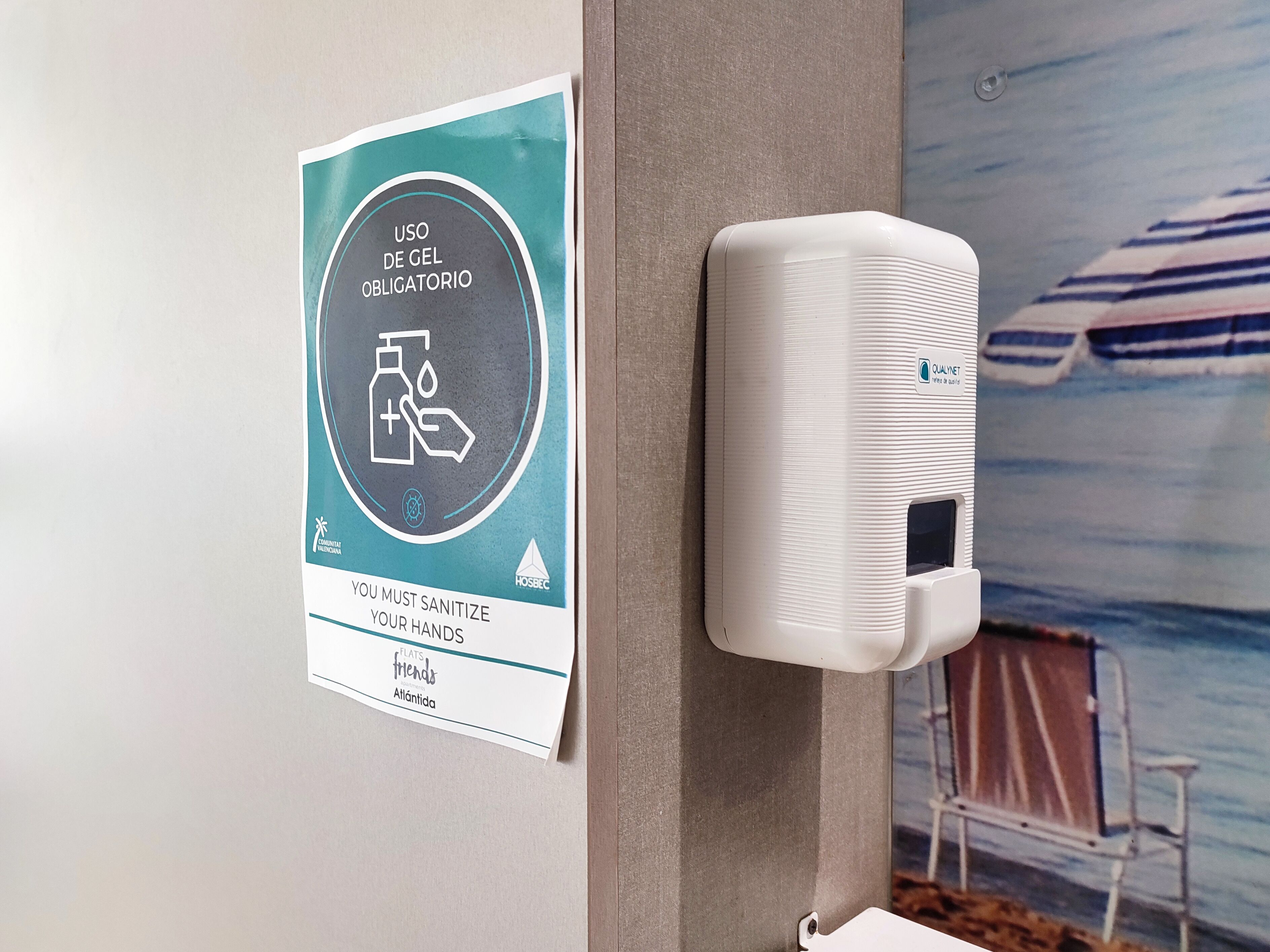 A hand sanitizer dispenser mounted on a wall with a sign above it.