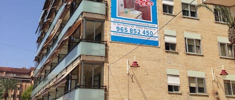 Un immeuble à plusieurs étages sur lequel est affichée une grande publicité pour un hôtel, avec une vue sur la plage, un numéro de téléphone et l’adresse de son site web.