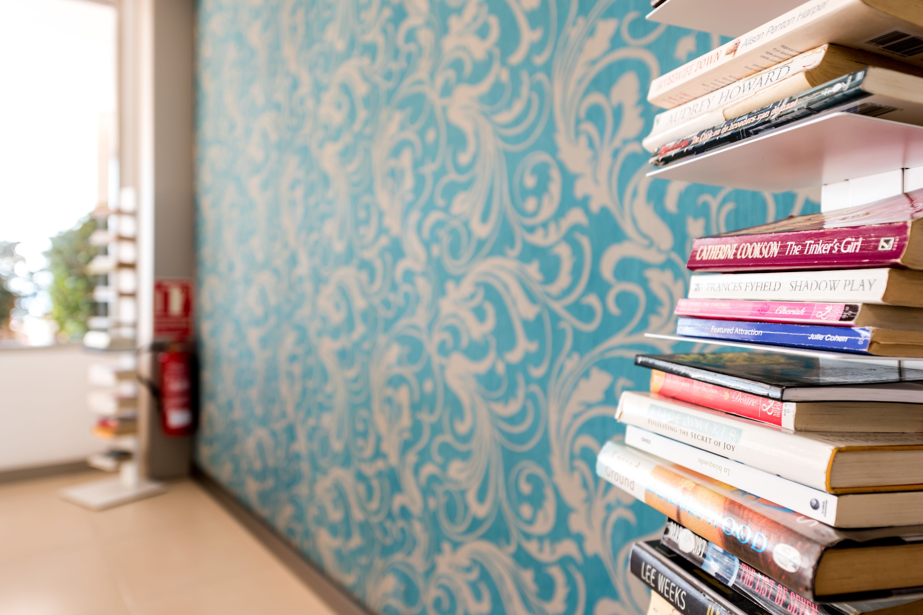 Een stapel boeken voor een muur met een patroon.