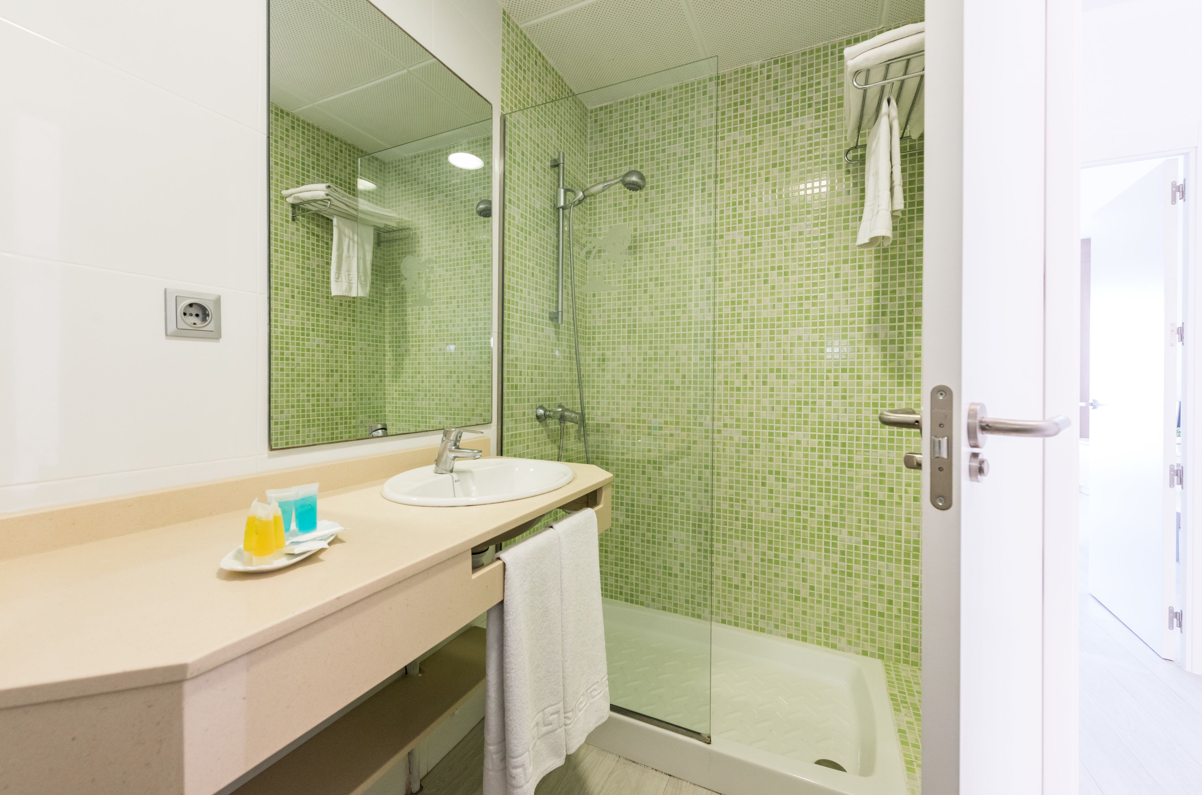 Een badkamer met een wastafel, spiegel, douche en glazen deur.