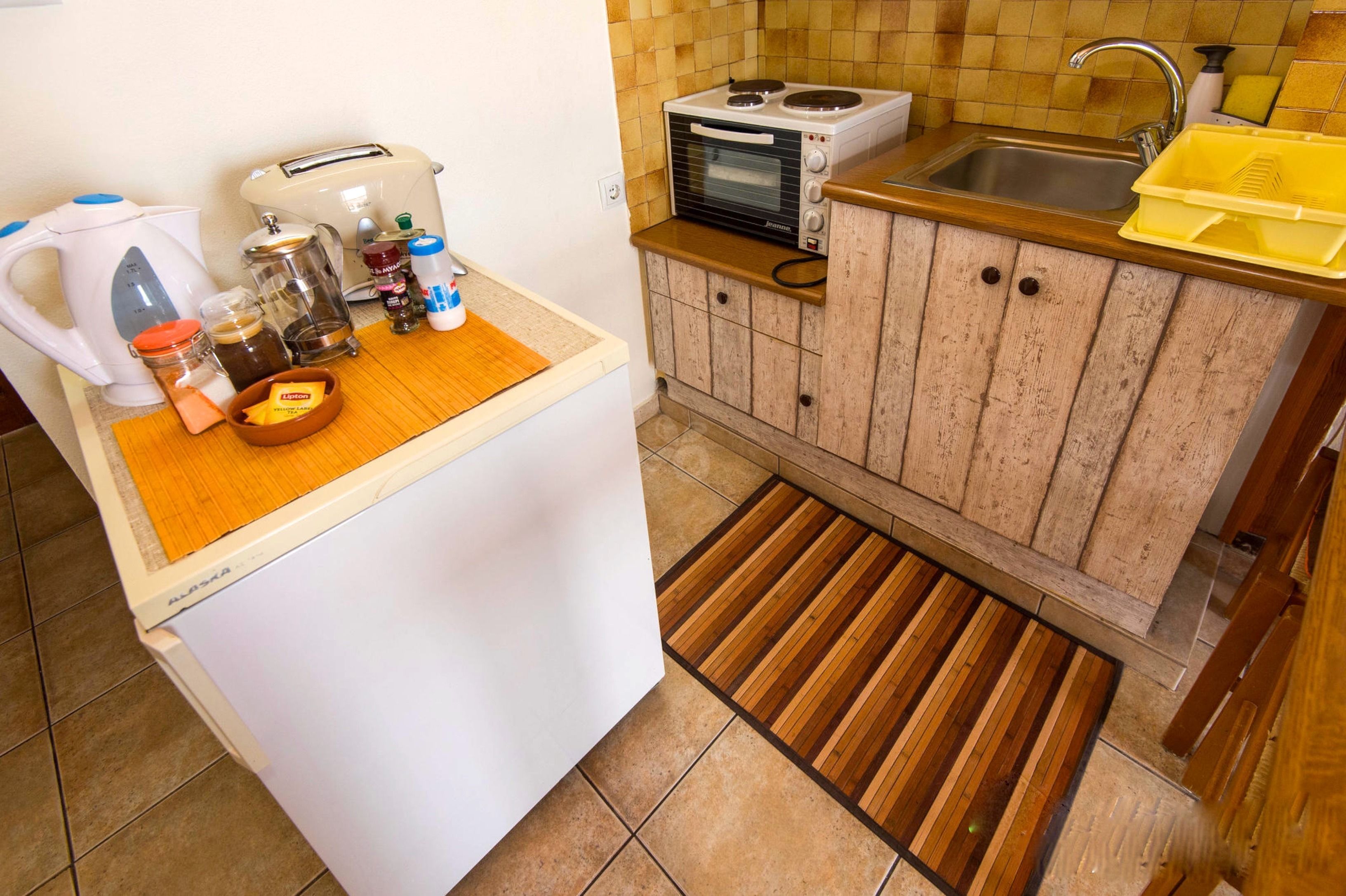 A compact kitchen with a refrigerator, a toaster, a coffee maker, a microwave, and a sink.