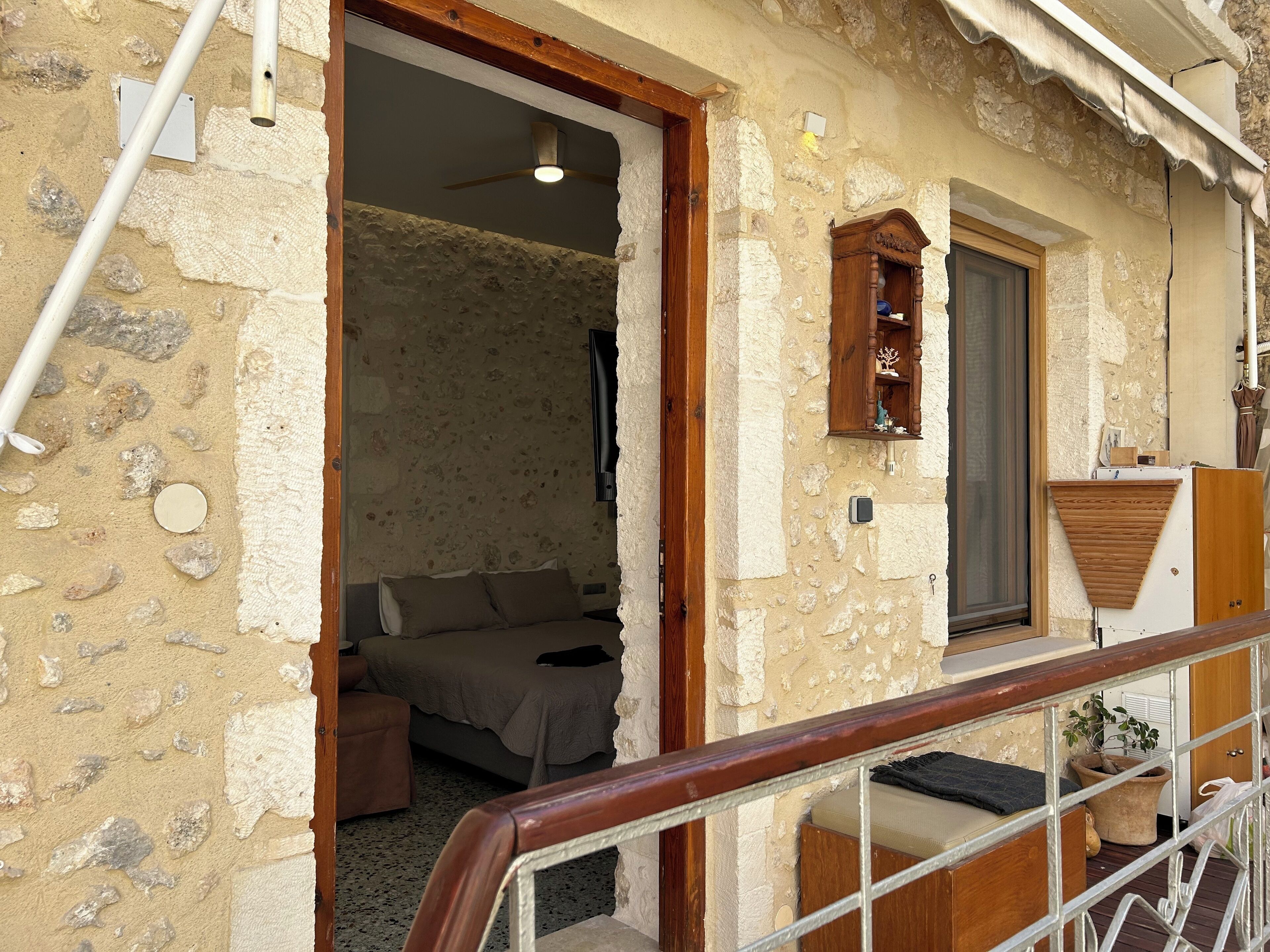 A stone-walled room with a bed, a wooden cabinet, and a window.