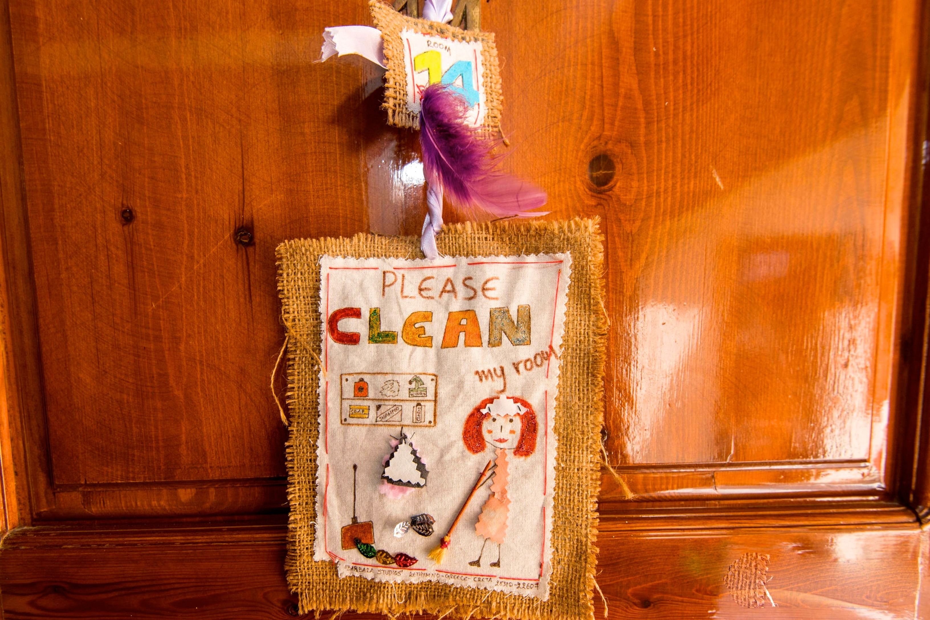 A wooden door with a handmade sign that says "PLEASE CLEAN my room."